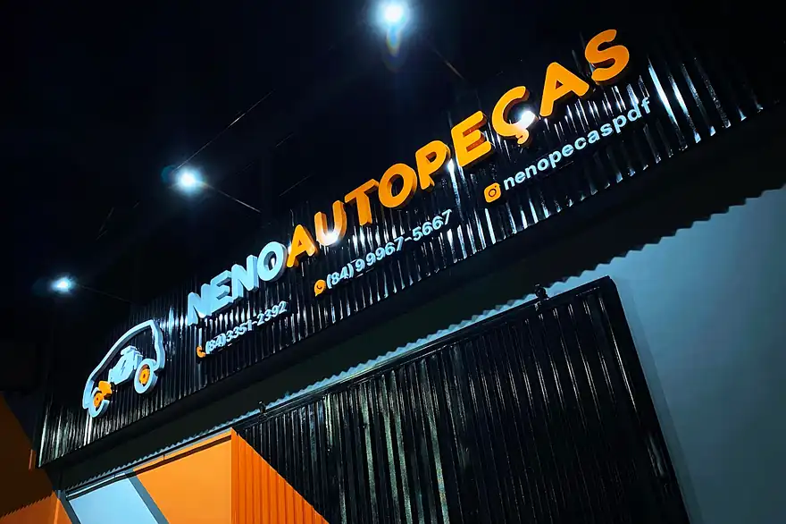 Fachada da Neno Autopeças com o letreiro aceso à noite, em Pau dos Ferros